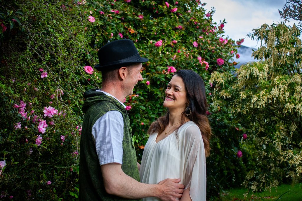 Happy couple in front of bushes and pink flowers